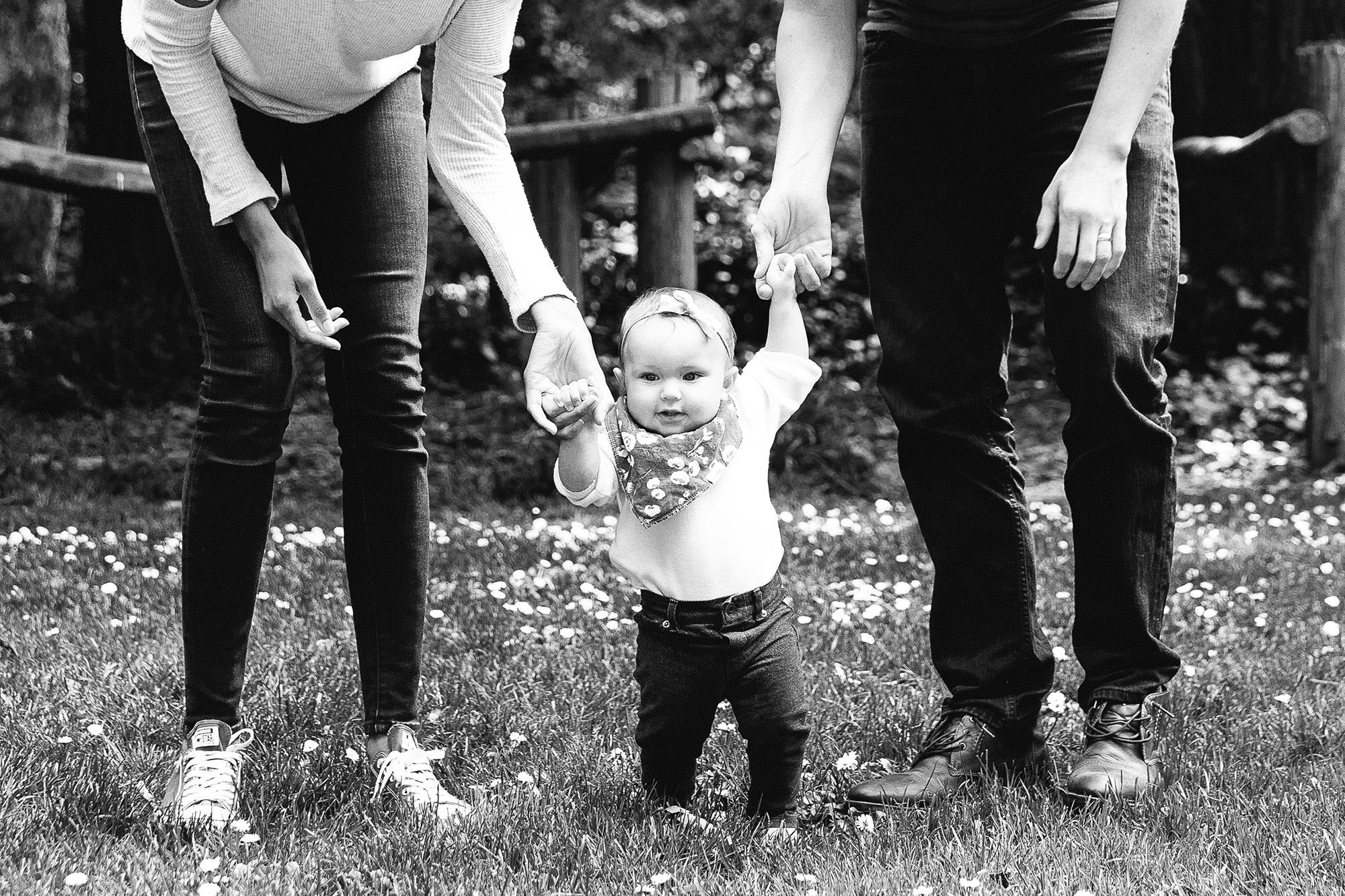 8 month hold holding her parents hands and walking